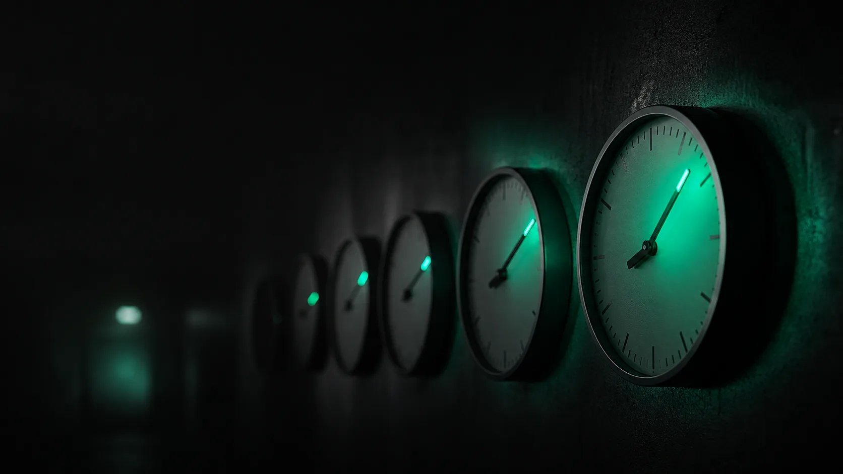 A row of dark analog clocks in a hallway, the first glowing teal and spilling its light onto the next, each set further past the hour, the delay cascading down the row into darkness